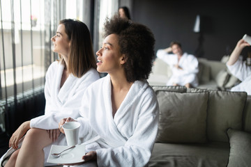 Women relaxing and drinking tea in robes during wellness weekend