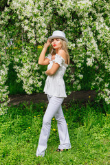 Sexy modern bride in white cylinder hat enjoing bloomin apple tree flowers.