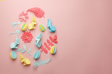 Easter egg shape made of various Easter origami paper craft decorative elements on pink background. Minimal spring concept. Flat lay.