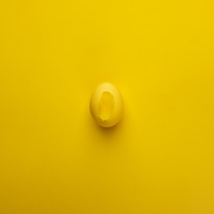 Happy Easter concept. Flat lay. Minimal concept. Top view. Yellow colorful Egg on bright yellow background, modern monochrome conceptual easter