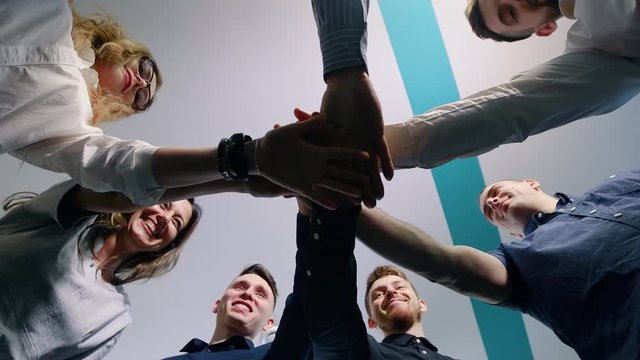 Successful team in office: many hands holding together standing in circle. Team building concept.