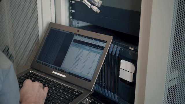 Engineer Working Laptop Computer. Server IT Engineer In Data Center Server Room.Server Room Works.Programmer Checks A work Of Server At A Data Center. 