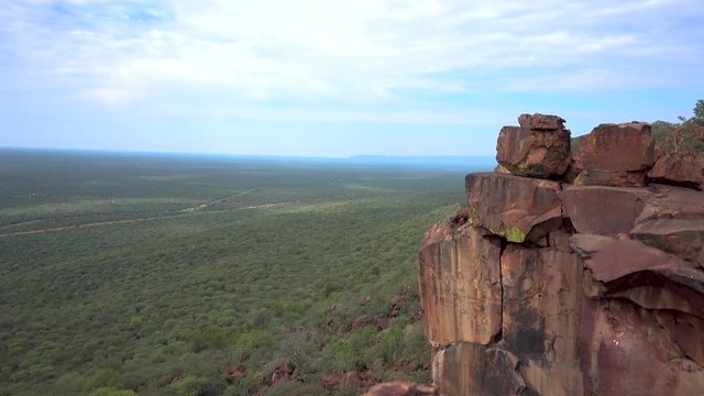 Static Wideshot of African Vegetation with Rock formation in Foreground. Lots of Green. Seeing in Far Distance