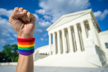 Hand wearing gay pride rainbow wristband making a power fist gesture outside the Supreme Court...