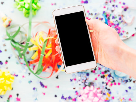 Mobile phone in hand above party decor