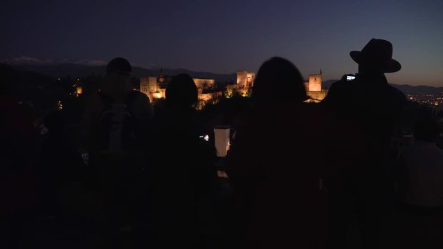 Silhouette of tourists taking photos of the Alhambra during after the sunset.