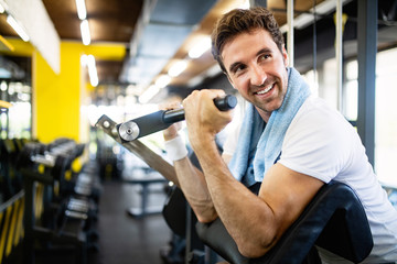 Fototapeta na wymiar Handsome happy fit man doing exercises in gym