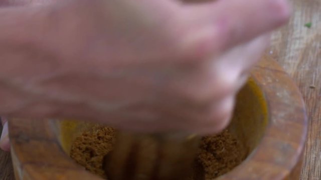 Grinding spices by hand with a mortar and pestle ready to add to a curry