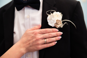 Wedding boutonniere on suit of groom and the hand of bride 