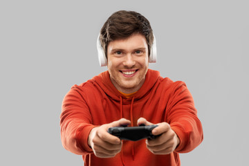 technology, gaming and people concept - young man or gamer in headphones with gamepad playing video game © Syda Productions