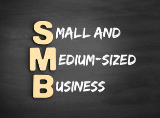 Wooden alphabets building the word SMB - Small and Medium-Sized Business acronym on blackboard