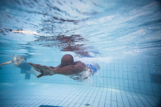 Underwater image of a male swimmer diving and swimming in a swimming pool to train