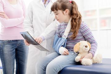 Doctor showing an x-ray to a young patient with broken arm