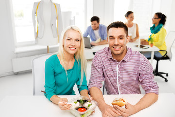corporate, food and people concept - happy colleagues having lunch and eating at office