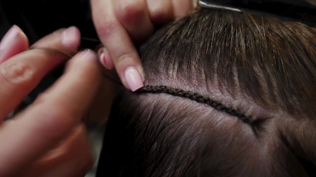 Hairdresser hair extensions brunette girl. Braiding braids for subsequent hair extensions. 4K