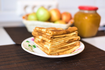pancakes on a plate with honey and chocolate. stacked pyramid. on the background of a jar of honey and apples. carnival