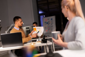 business, deadline and people concept - man showing papers to colleague late at night office