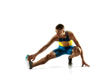 Young caucasian man warming up before run isolated on white studio background. One male runner or jogger. Silhouette of stretching athlete with shadows.