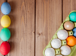 Colorful Easter eggs in box on wooden background with copy space