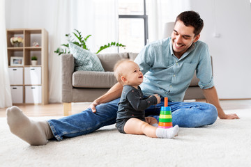 family, fatherhood and people concept - happy father and little baby daughter playing with pyramid...