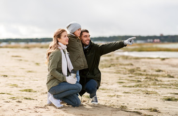 family, leisure and people concept - happy mother, father and little daughter on autumn beach