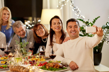 celebration, holidays and people concept - happy family having dinner party at home and taking selfie by smartphone