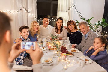 celebration, holidays and people concept - happy family having dinner party at home and taking selfie by smartphone