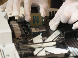 Detail of expert hands in white cloves at processor replacement. Close-up of installation a central processing unit into a socket on computer mainboard.. Working of technical support engineer.