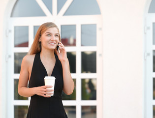 Businesswoman using mobile phone and drinking coffee on a break at outdoor