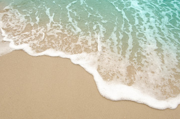Fototapeta na wymiar Light blue ocean waves on the background sand beach