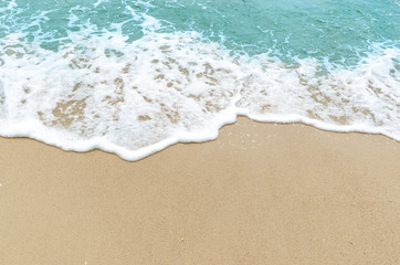 Fototapeta na wymiar Light blue ocean waves on the background sand beach