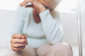 Obraz na płótnie Canvas Heartbroken elderly woman holding a wedding ring