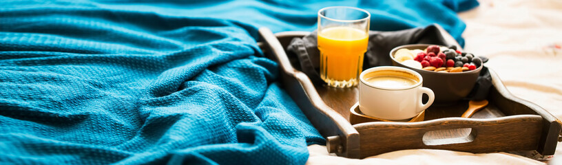 Bed breakfast with glass of orange juice and a bowl of oatmeal with fresh berries, banana and...