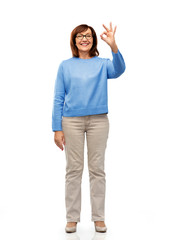 Fototapeta premium gesture, vision and old people concept - portrait of smiling senior woman in glasses showing ok hand sign over white background