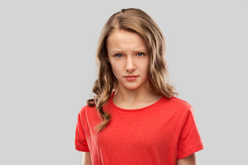 emotion, expression and people concept - sad or angry teenage girl in red t-shirt over grey...