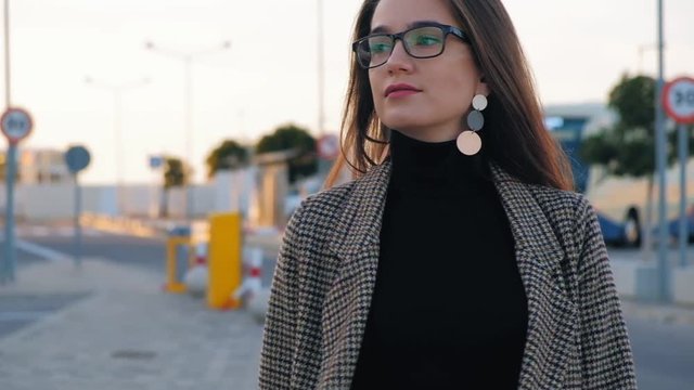 Slow motion of young business woman in glasses walking confidently along the street