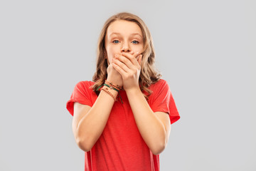 emotion, expression and people concept - speechless teenage girl with long hair in red t-shirt covering her mouth by hands over grey background
