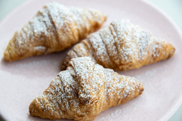 Fresh baked croissants with sugar on a plate