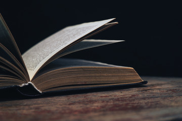 One open old book on a round wooden table. Beautiful dark background...