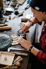 man replacing the jewel while sitting at the table in the workshop. close up cropped side view photo