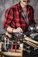happy craftsman sitting at the table at work in the room with gray wall