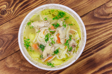 Chicken soup with noodles and vegetables on wooden table. Top view