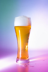 Full glass of light beer. Multi-colored lights. Close-up.