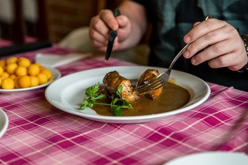 Hands cut meat at restaurant table.