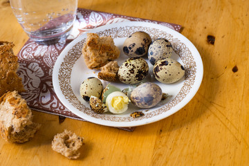 Boiled quail eggs on plate, bread and glass of water.