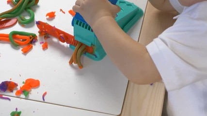 A two years old preschool child playing with modeling clay (compound). Smiling and looking at the camera. Early childhood education to children concept