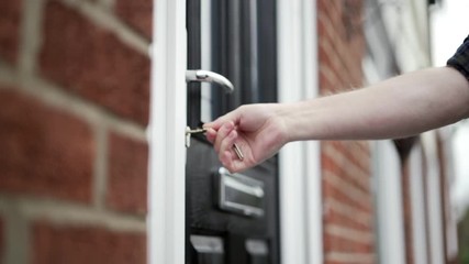 Locking black front door with house keys.