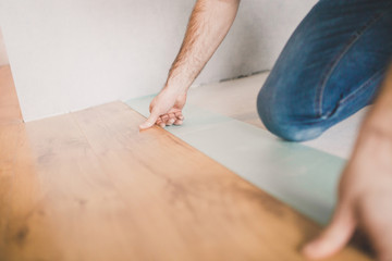 The builder is engaged in laying laminate in the room - repair and finishing work