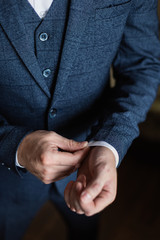 Businessman in a white shirt straightens cuffs, standing at the window in natural light. Man buttons cuff-link on French cuffs sleeves luxury white shirt. Concept successfully bisinesman