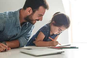 Father teach his daughter to draw.They sitting in living room.Education and family concept.